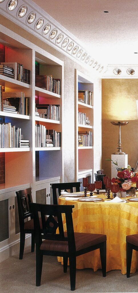 A dining room with tables and chairs, and bookcases.