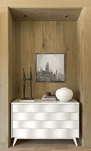 A white dresser in a room with wooden walls.