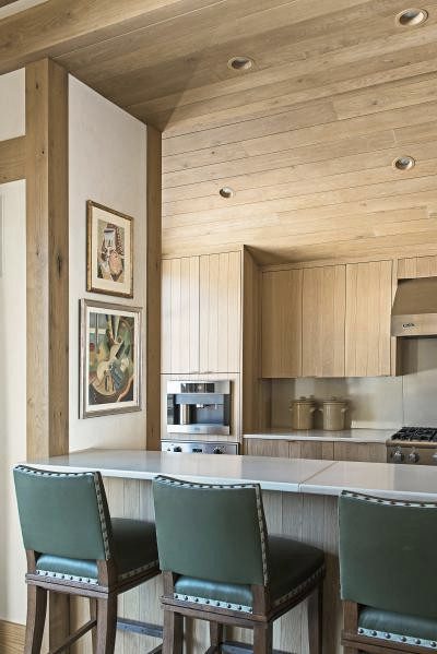 A kitchen with green stools and wood paneled walls.