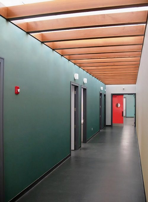 A hallway with green walls and a red door.