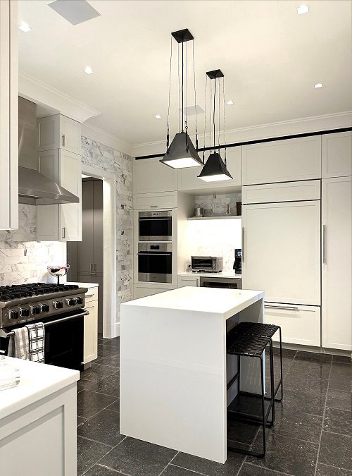 A modern kitchen with white cabinets and black counter tops.