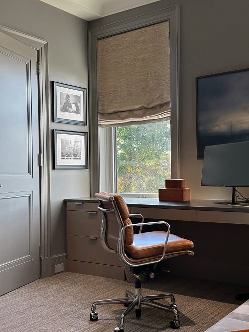 A home office with a desk, chair and window.