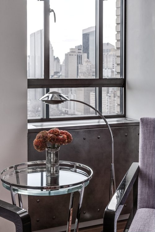 A room with a glass table and chairs and a view of the city.