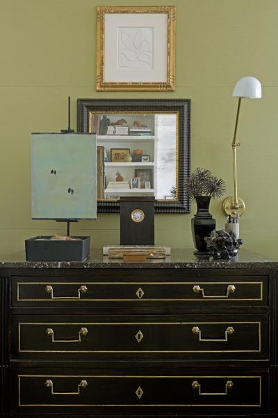 A black dresser with a clock and a lamp.