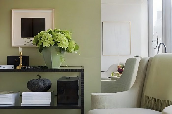 A living room with green walls and white furniture.