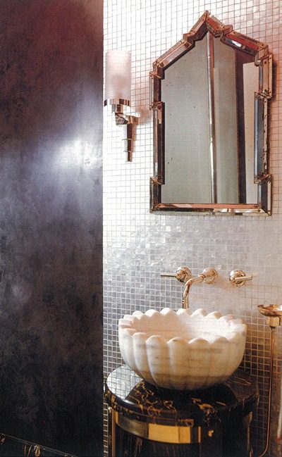 A bathroom with a gold sink and mirror.