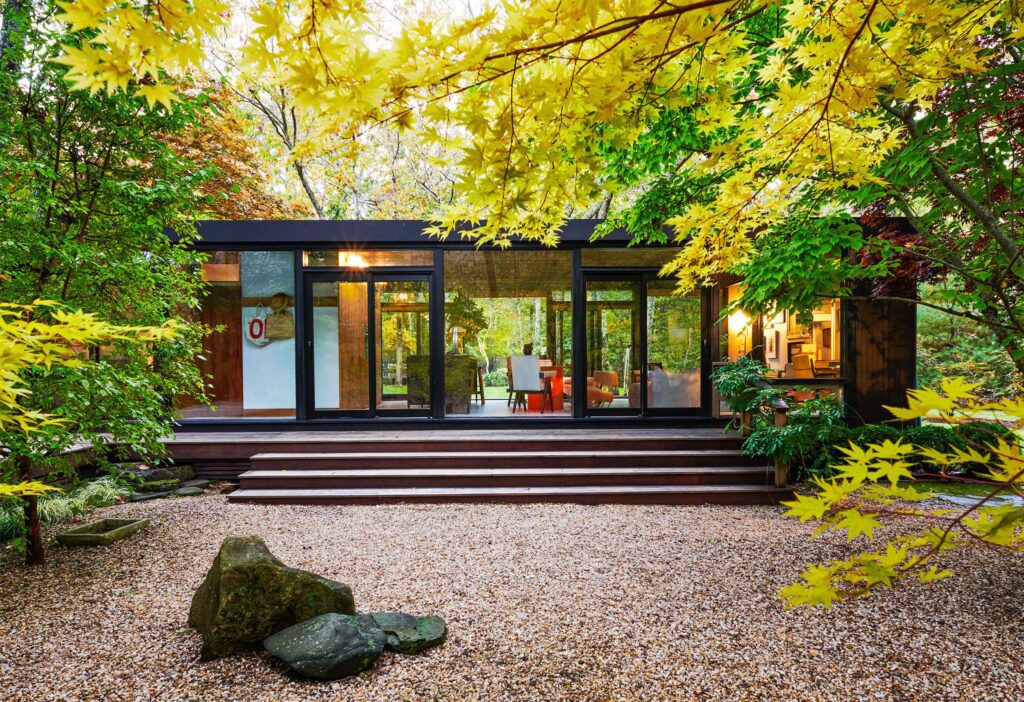 Modern glass house surrounded by autumn foliage