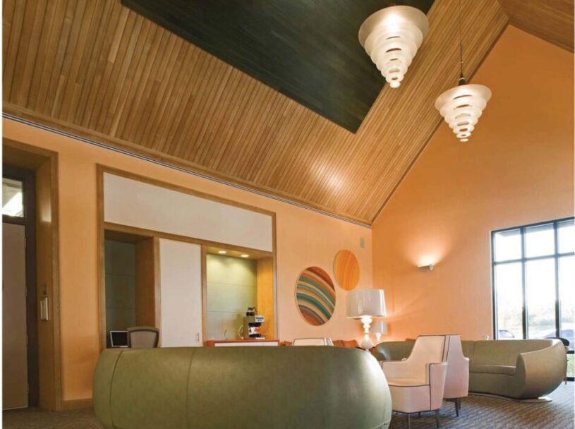 Warm contemporary oncology clinic waiting area with curved seating, wood ceiling, and patient-centered design