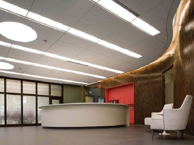Contemporary oncology clinic reception area with curved wood walls, circular reception desk, and soft natural lighting