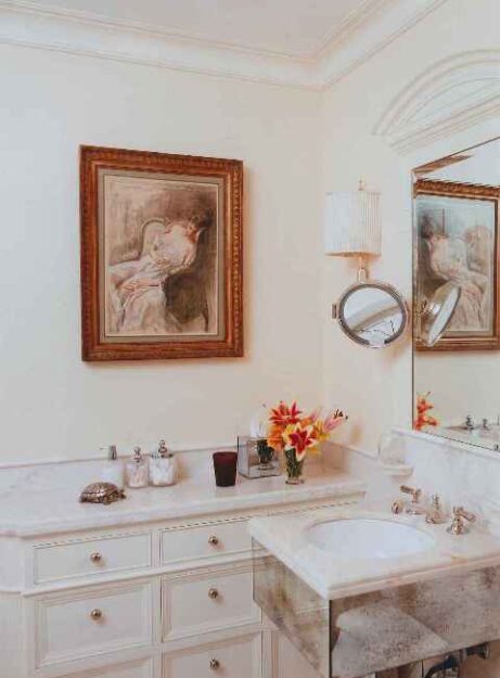 Neo-Classical powder room in Upper East Side townhouse with custom mirrored detailing and marble vanity