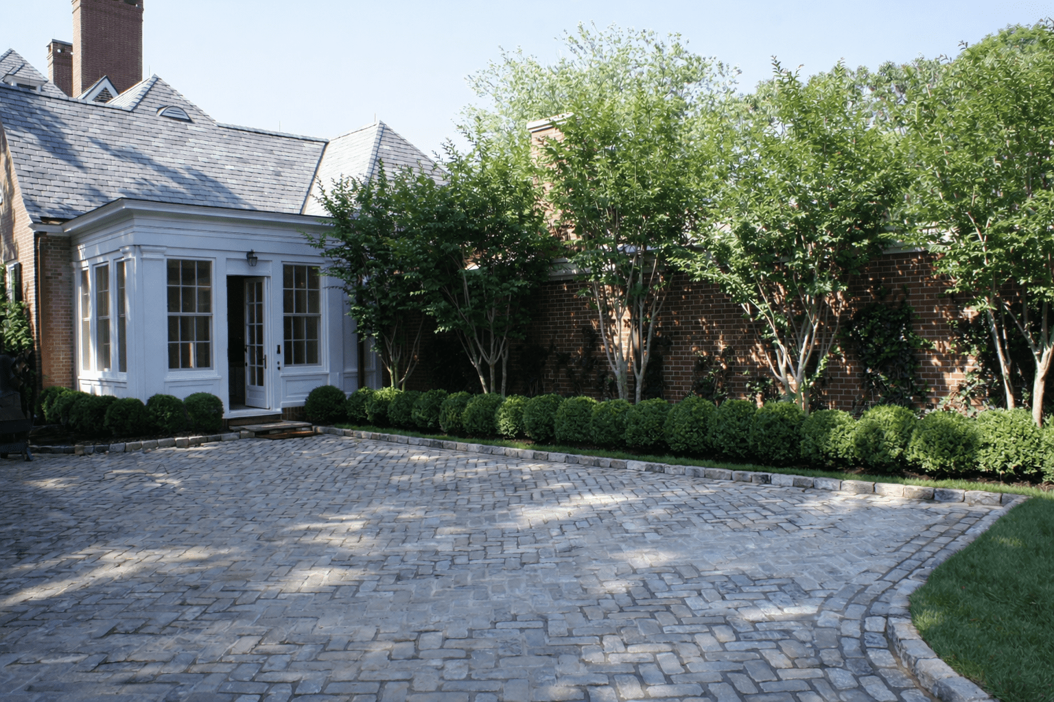 Historic Southampton estate courtyard with brick architecture, formal landscaping, and traditional stone paving