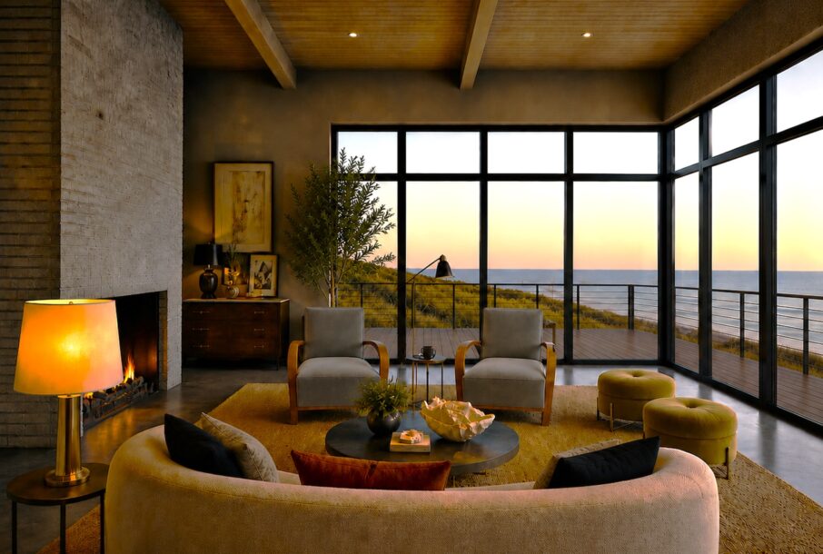 Modern coastal living room with floor-to-ceiling steel windows, warm wood ceiling, and panoramic ocean views